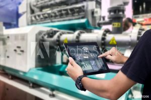 Smart industry control concept.Hands holding tablet on blurred automation machine as background